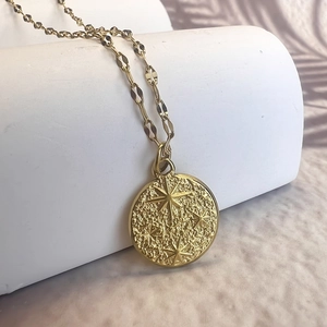 Detailed view of vintage gold star embossed coin pendant on flat link chain