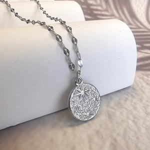 Macro detail of silver coin pendant with hammered texture and eight-pointed star engraving