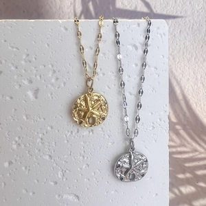 Gold and silver stainless steel necklaces with textured starfish pendants on stone board