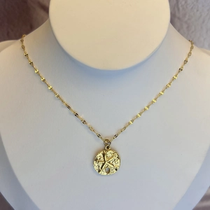 Golden stainless steel round necklace with embossed starfish pendant on a display stand