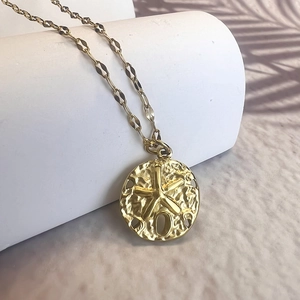 Detail of gold starfish pendant on hammered round disc with bohemian chain link
