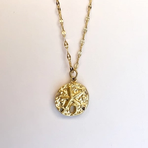 Detailed view of golden starfish embossed coin pendant with hammered metal texture