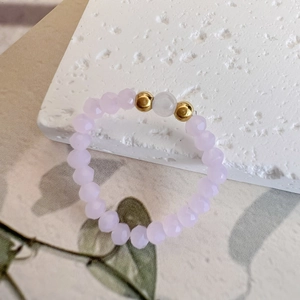 Macro detail of elastic beaded ring with pink faceted stones and gold accents