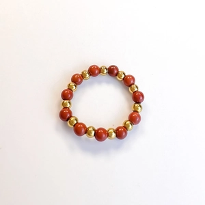 Detail of red stone beads and golden stainless steel beads on an elastic ring