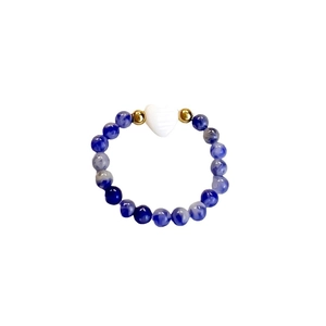 Anello con perline blu marmorizzate, dettagli dorati e ciondolo a cuore bianco su sfondo bianco