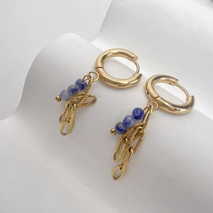 Dettaglio di orecchini a cerchio dorati 18K con pietre blu e ciondoli a catena irregolari