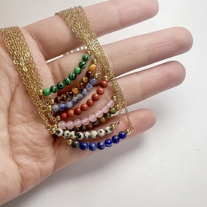 Minimalist gold chain necklace featuring colorful natural stone beads in hand