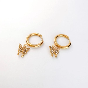 Détail de boucles d'oreilles papillon dorées avec incrustation de zircon et fermoir créole