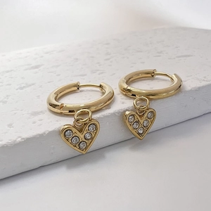 Détail de créoles dorées avec pendentifs en forme de cœur et pierres de cristal