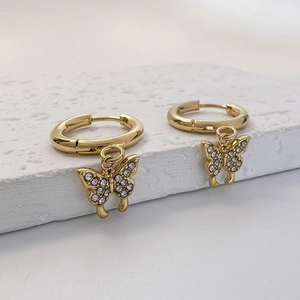 Détail macro de boucles d'oreilles créoles papillon dorées avec zircons blancs