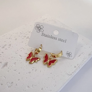 Polished gold stainless steel butterfly earrings with red oil drip on a stone stand