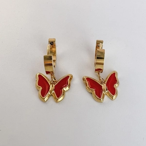 Close-up of golden butterfly earrings with vibrant red enamel on a clean white background