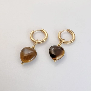 Detail view of heart-shaped tiger eye stone pendant earrings with golden hoops