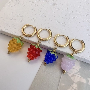 Detailed close-up of colorful resin grape charms on gold hoop earrings in natural light