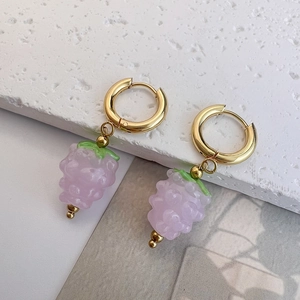 Macro view of light purple grape pendant earrings with gold hoops and green leaf detail