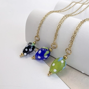 Trois colliers avec pendentifs fraises en verre vert, bleu et noir sur des chaînes dorées