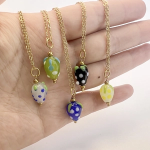 Lot de cinq colliers en acier inoxydable doré avec pendentifs fraises en verre coloré