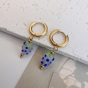 Macro shot of gold hoop earrings featuring handmade blue-dotted glass strawberry charms
