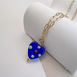 Detail of blue glass heart pendant with colorful dots on a chunky gold chain necklace