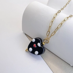 Detail of black glass heart pendant with polka dots on a gold stainless steel chain