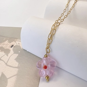 Detail view of pink glass flower pendant on gold stainless steel link chain necklace