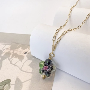 Detailed macro view of colorful glass flower pendant on a gold oval link chain