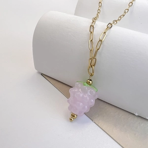 Detailed view of a purple glass raspberry pendant on a gold rectangular link chain