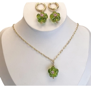 Floral necklace and earring set with green glass petals and gold chain on model