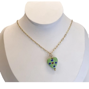 Gold stainless steel necklace with green glass heart pendant on jewelry display stand
