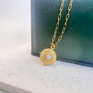 Détail du collier pendentif soleil doré serti d'une pierre blanche marbrée naturelle