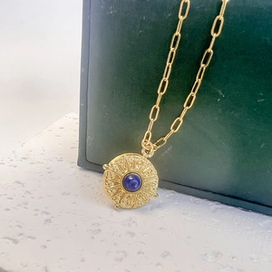 Détail du collier pendentif étoile dorée avec pierre bleue sur support de luxe