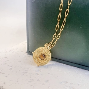 Vue macro du collier à maillons dorés avec pendentif pièce soleil et turquoise