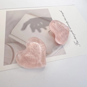 Close-up of pink heart stud earrings with marble resin texture and stainless steel pins
