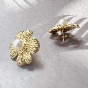 Vintage matte gold flower earrings with white pearl center on marble background