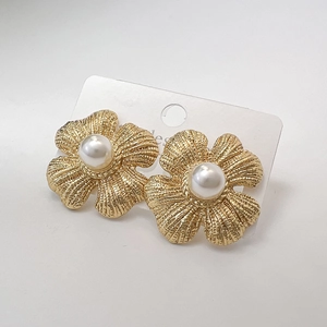 Macro shot of gold flower earrings with ribbed metal petals and central white pearl detail