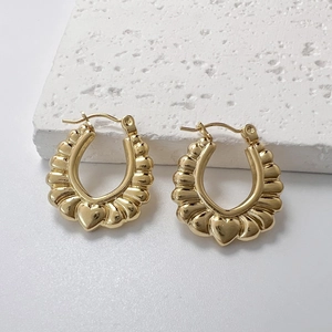 Détail de boucles d'oreilles en U dorées avec texture plissée et charme de coeur 3D