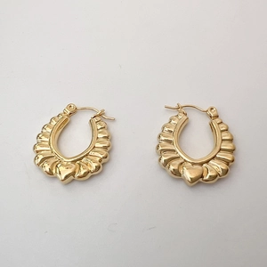 Gros plan sur des boucles d'oreilles dorées en U avec détail de cœur 3D poli