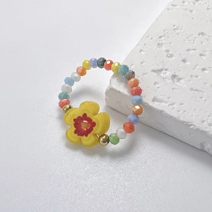 Detailansicht des Perlenrings mit bunten Glasperlen und einem gelben Gänseblümchen-Anhänger