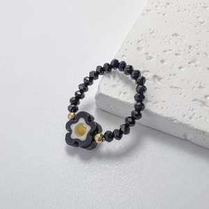Detailansicht des elastischen Blumenrings mit schwarzen Facettenperlen und gelbem Blumenmotiv