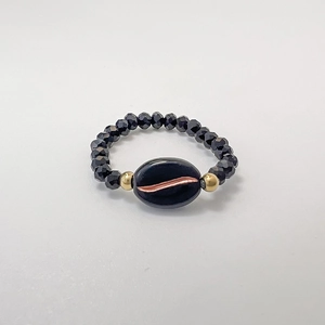 Detailed view of beaded stretch ring featuring black faceted beads and gold accents