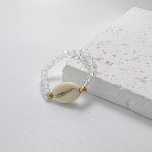 Detail of beaded ring with white oval coffee bean charm and golden metal accents