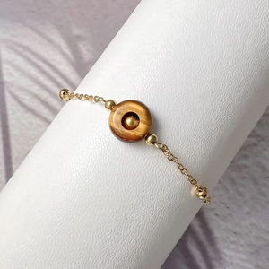 Macro shot of gold-plated stainless steel bracelet with a tiger eye stone donut pendant