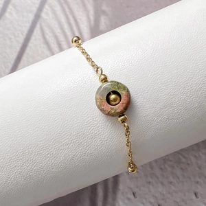 Detail of bohemian gold titanium steel bracelet with natural pink green stone bead
