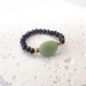 Macro dettagliata di un anello di perline con pietra naturale ovale verde su pietra bianca