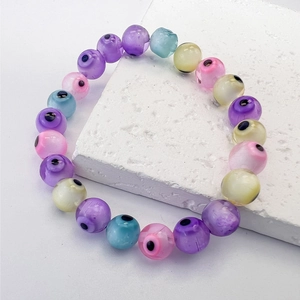 Macro shot of colorful Nazar evil eye glass beads on a stretch bracelet against white stone