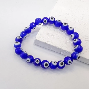 Close-up of blue glass evil eye beads elastic bracelet on a white stone background