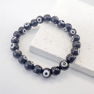 Detailed view of evil eye glass beads on a black beaded elastic bracelet over a stone base