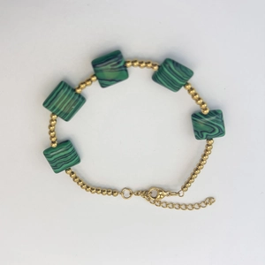 Detail of beaded gold bracelet featuring green malachite stones and adjustable lobster clasp