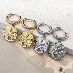 Titanium steel sand dollar star earrings in gold and silver finishes on stone background