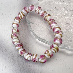 Gros plan de perles en verre faites main avec motifs de roses roses et feuille d'or